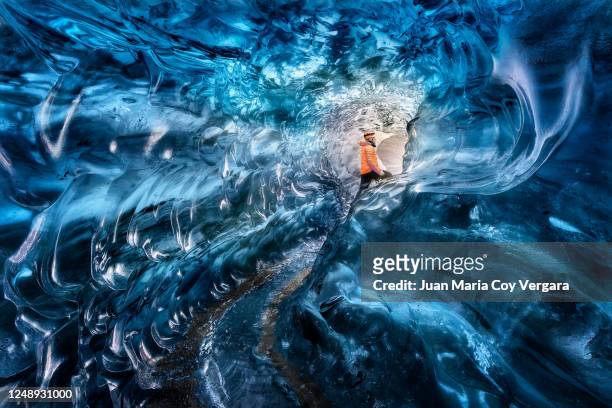 man ice climber exploring a blue ice cave in vatnajokull glacier, golden circle route, iceland - außergewöhnliche sportarten stock-fotos und bilder