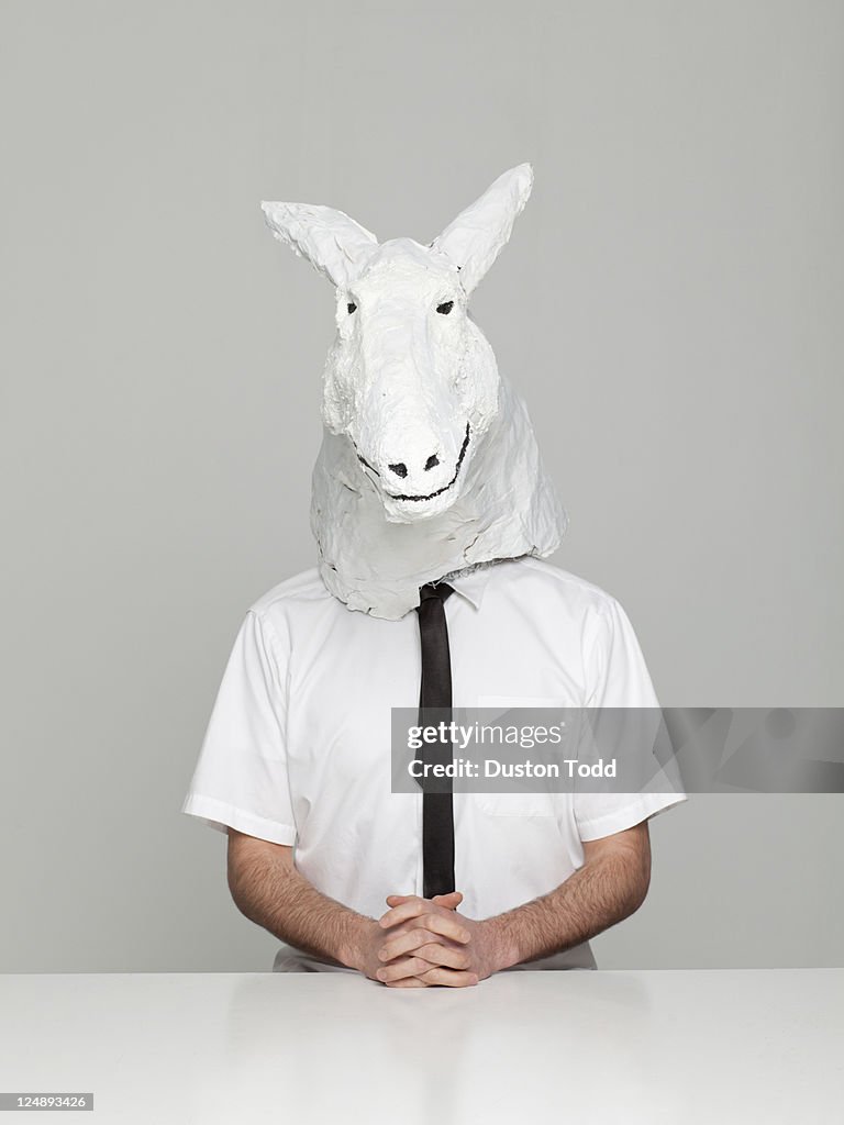 Studio portrait of young man wearing horse mask