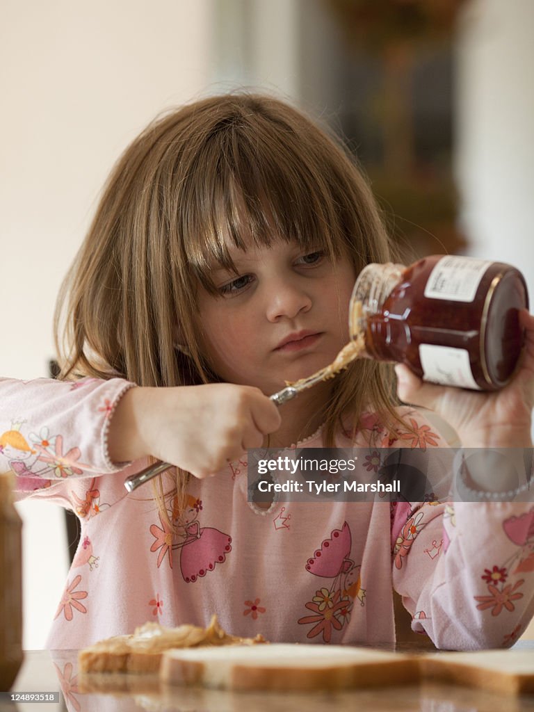 USA, Utah, Cedar Hills, Girl (4-5) putting jam on bread