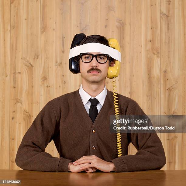 businessman with telephones strapped to head in office - nerd stockfoto's en -beelden