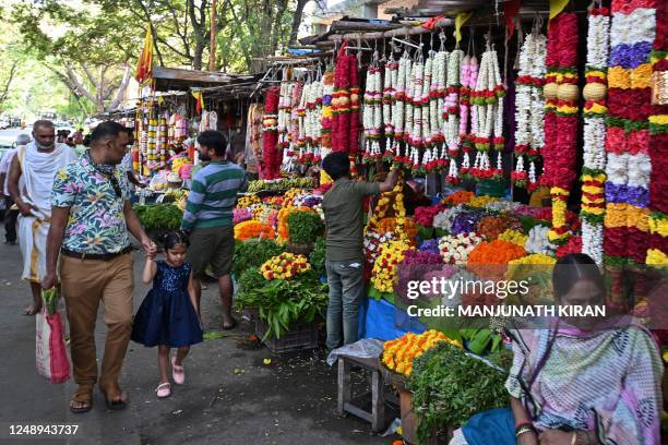 People walk past stalls selling flower garlands at a flower market in Bengaluru on March 21 on the eve of 'Ugadi', a festival celebrated as New Years...