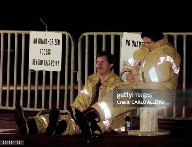 Two firefighters rest at a check point in Peggy's Cove, Nova Scotia, Canada 03 September after spending all day searching for bodies from Swissair...