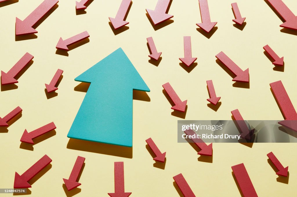One big arrow moving in the opposite direction to a crowd of small arrows