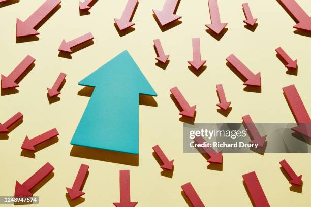 one big arrow moving in the opposite direction to a crowd of small arrows - unconventional imagens e fotografias de stock