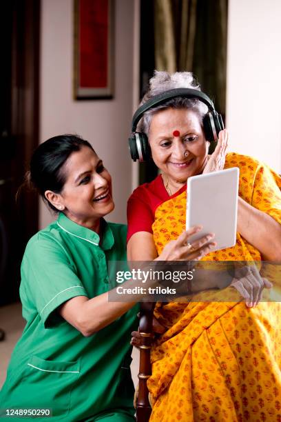 nurse with senior women listening music at home - female nurse stock pictures, royalty-free photos & images