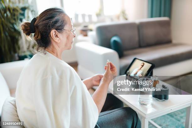 senior woman video calling with female healthcare person - healthcare innovation stock pictures, royalty-free photos & images