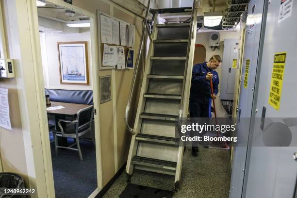 Crew member sweeps the deck of the US Coast Guard 'Katmai Bay' Cutter ship while mooring at Lime Island following ice clearing operations in Sault...