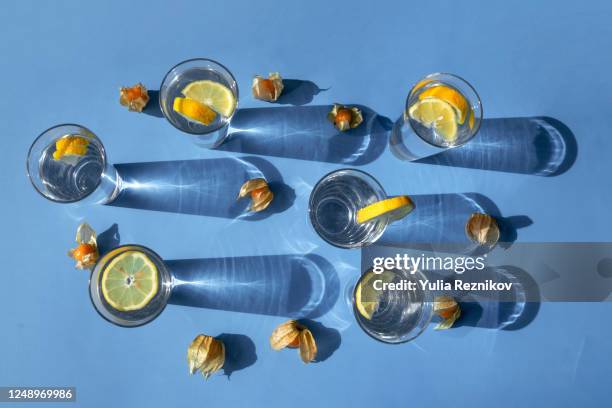 top view of glasses with lemon on the blue background - lemon soda stock pictures, royalty-free photos & images