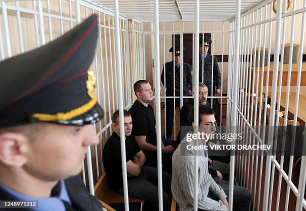 Top Belarus opposition leader Andrei Sannikov sits with his co-defendants in a courtroom's cage during his trial in Minsk, on April 27, 2011....