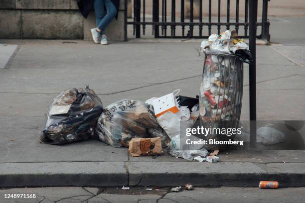 An overflowing garbage bin and bags of trash during a sanitation workers strike near Luxembourg gardens in Paris, France, on Tuesday, March 21, 2023....