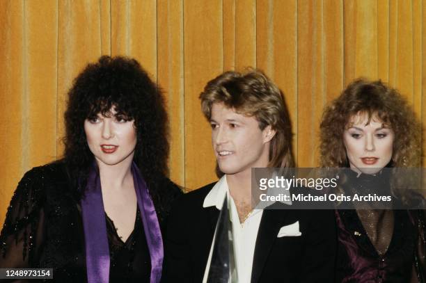 Singers Ann and Nancy Wilson of the rock band Heart with singer Andy Gibb at the American Music Awards, USA, 18th January 1980. Gibb is accepting the...