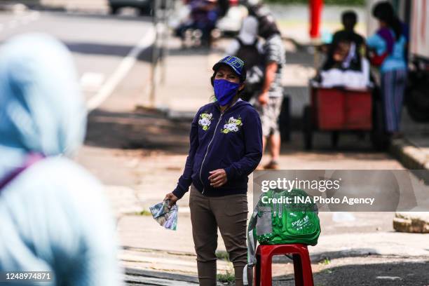 Currency exchange service vendor wearing a protective face mask while waiting for consumers on the sidewalk in Bandung, Indonesia, May 22, 2020....