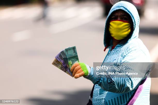 Currency exchange service vendor wearing a protective face mask while waiting for consumers on the sidewalk in Bandung, Indonesia, May 22, 2020....