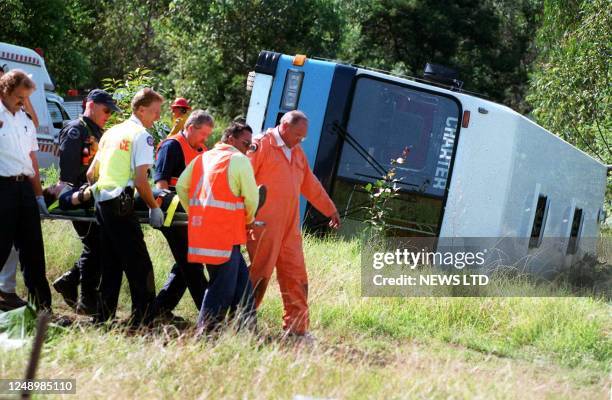 Emergency services workers carry an seriously injured child away after their bus overturned in the Hunter Valley north of Sydney 14 April 1999. Two...