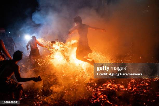 Balinese man kicks burn coconut husks during the fire fight ritual called Mesabatan Api on March 21, 2023 at traditional sub village of Nagi, in...