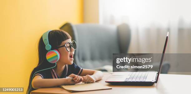 年輕的亞洲可愛的女孩學習與筆記型電腦在家裡大流行期間 - homeschool 個照片及圖片檔
