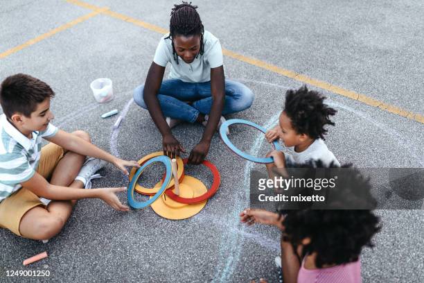 donna con bambini che giocano al gioco del toss dell'anello - bambini seduti in cerchio foto e immagini stock