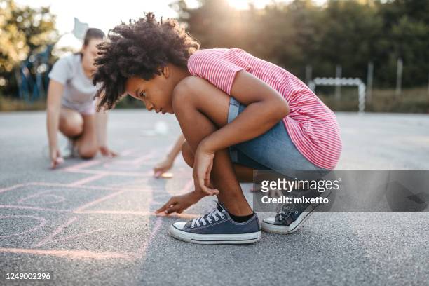 friends drawing hopscotch court using chalk - hopscotch stock pictures, royalty-free photos & images