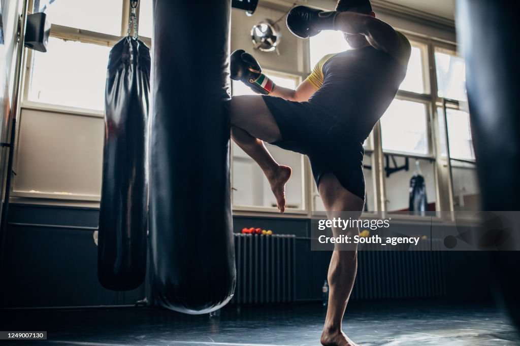 Man kick boxer training alone in gym