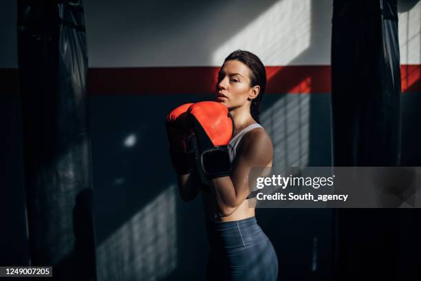 pugile donna in piedi da sola in palestra - boxing womens foto e immagini stock