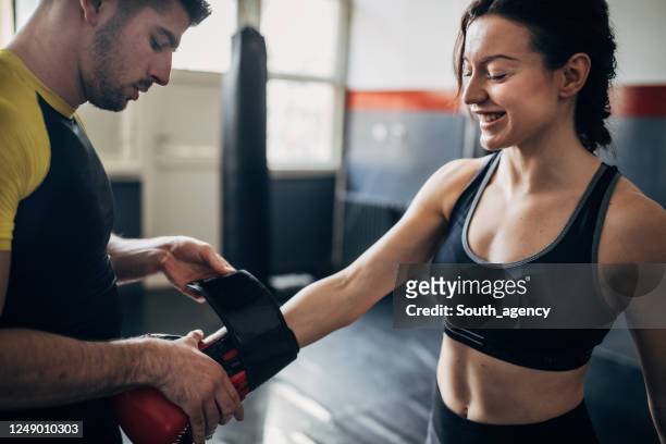 male coach wrapping boxing glove on female boxer hands - boxing gloves stock pictures, royalty-free photos & images