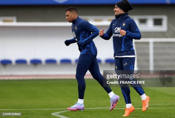 France's forward Kylian Mbappe and France's forward Antoine Griezmann run during a training session in Clairefontaine-en-Yvelines on March 21, 2023...
