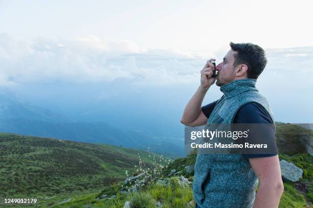 young man using asthma inhaler during a hike - man inhaler stock pictures, royalty-free photos & images