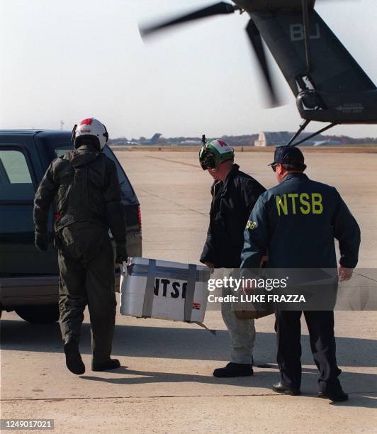 Government officials carry a case containing the flight data recorder also known as the "black box" which was flown via helicopter to Andrews Air...