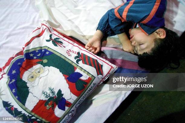 Child victim of the Venezuelan floods sleeps at a shelter set up at a local Caracas stadium 23 December, 1999. Un nino cuya familia perdio su casa,...