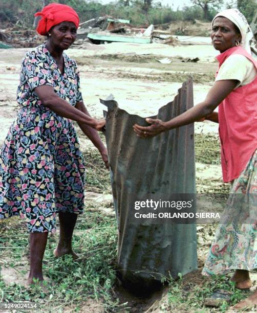 Dos mujeres garifunas del atlantico de Honduras tratan el 01 de Noviembre 1998 de recuperar entre la arena una lamina de zinc, para proceder a...