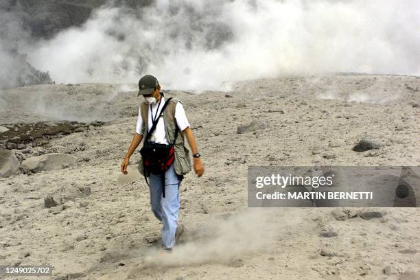 Member of the press is seen wearing a face mask walking on lava and rocks in Rio Market, Ecuador 04 November 2002, the morning after the volcano El...