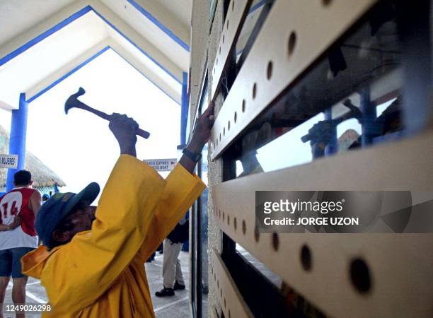 Man boards up a local commercial building 21 September 2002 in Cancun as Hurricane Isidore churns toward Mexico's Yucatan Peninsula after lashing...