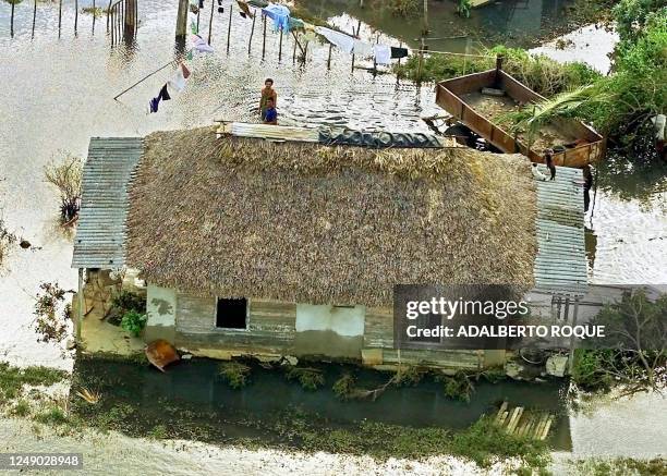 Man and his son are seen salavaging clothes as their home is inundated by the flood 07 November 2001 in Playa Giron, Cuba. Un hombre y su hijo...