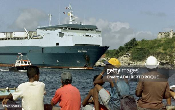 Havana residents watch as the Express container ship docks 16 December with 20 containers of frozen chicken, worth about 300,000 USD, shipped from...