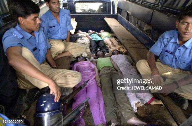 Police guard the dead bodies of garment factory workers who were killed in a stampede in their factory in Dhaka, 08 August 2001. At least 16 workers...