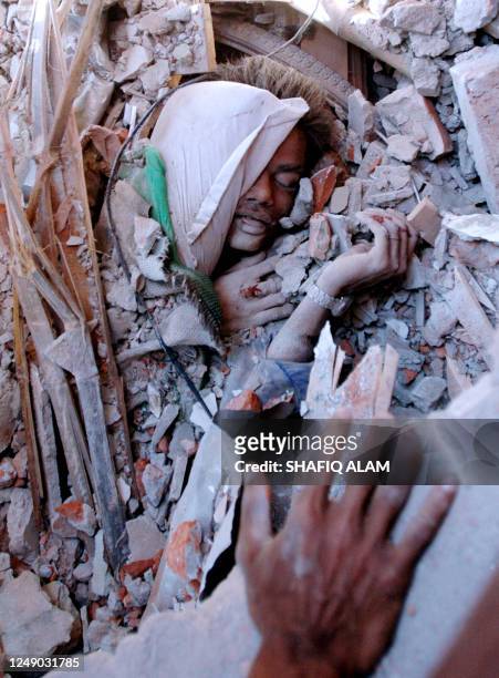 Bangladeshi rescuers try to rescue a victim buried in rubble at the site of a collapsed building in Dhaka, 25 February 2006. A five-storey building...