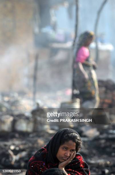 Woman looks on as she sits near the remains of her smouldering hut in New Delhi on January 31, 2012. Scores of slum huts were gutted in a devastating...