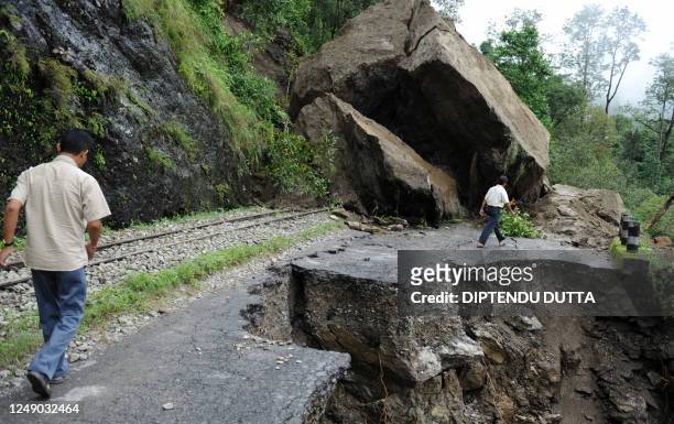 Indian local residents walk over the debris of a landslide on National Highway 55 at Kurseong village, some 56 km from the eastern Indian city of...