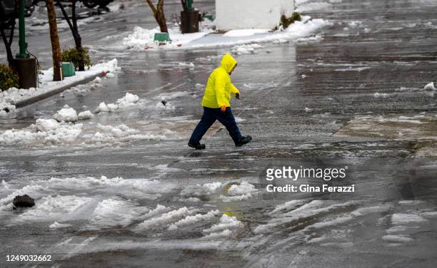 Worker for SoCal Gas Co. Walks across the slushy parking lot at Lake Arrowhead Village as sleet falls on the mountain community on March 21, 2023 in...