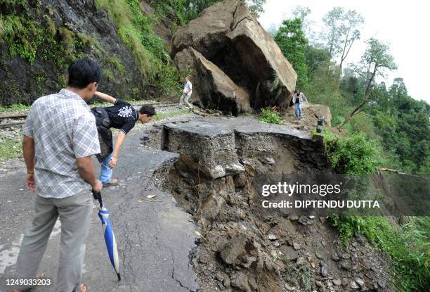 Indian tourists and local residents walk over the debris of a landslide on National Highway 55 at Kurseong village, some 56 km from the eastern...