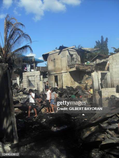 Residents walk through the debris of gutted houses after a fire broke out at a slum area in Bacolod City, central Philippines on November 2, 2009....
