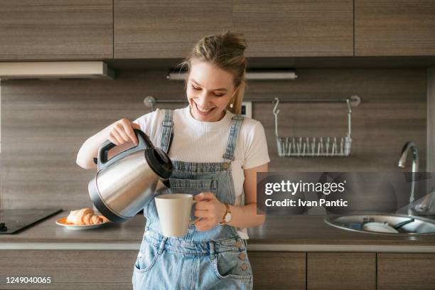 gelukkige jonge vrouw die zich sommige ochtendkoffie giet - coffee happy stockfoto's en -beelden