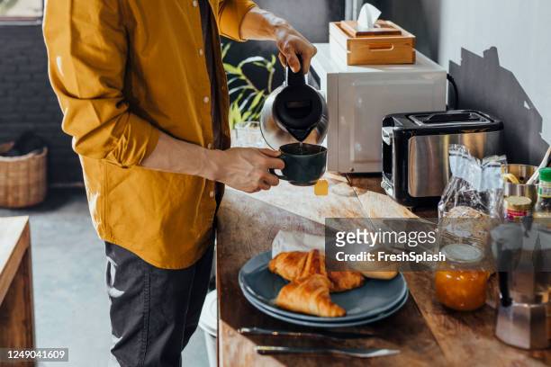 hombre asiático feliz haciendo el té en la cocina en la mañana - toaster fotografías e imágenes de stock