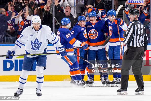 Hudson Fasching of the New York Islanders is congratulated by his teammates after scoring a goal as Timothy Liljegren of the Toronto Maple Leafs...
