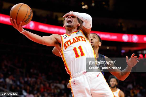 Trae Young of the Atlanta Hawks is fouled by Rodney McGruder of the Detroit Pistons during the second half at State Farm Arena on March 21, 2023 in...