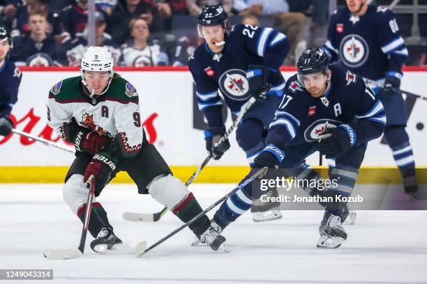 Clayton Keller of the Arizona Coyotes plays the puck down the ice away from Adam Lowry of the Winnipeg Jets during second period action at the Canada...