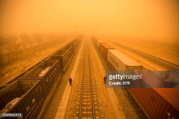 This photo taken on March 21, 2023 shows police officers checking train cars at a border checkpoint during a sandstorm in the border city of Erenhot,...