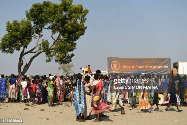 Internally displaced women wait for their food ration during a food distribution next to a World Food Programme truck in Bentiu on February 7, 2023....