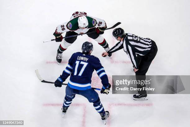 Laurent Dauphin of he Arizona Coyotes and Adam Lowry of the Winnipeg Jets get set for a third period face-off at the Canada Life Centre on March 21,...