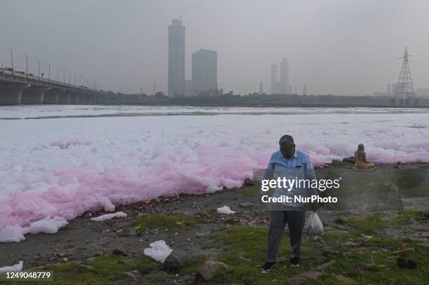 Man walks on the banks of river Yamuna covered with toxic foam caused by industrial discharge, on the eve of World Water Day, in New Delhi, India on...